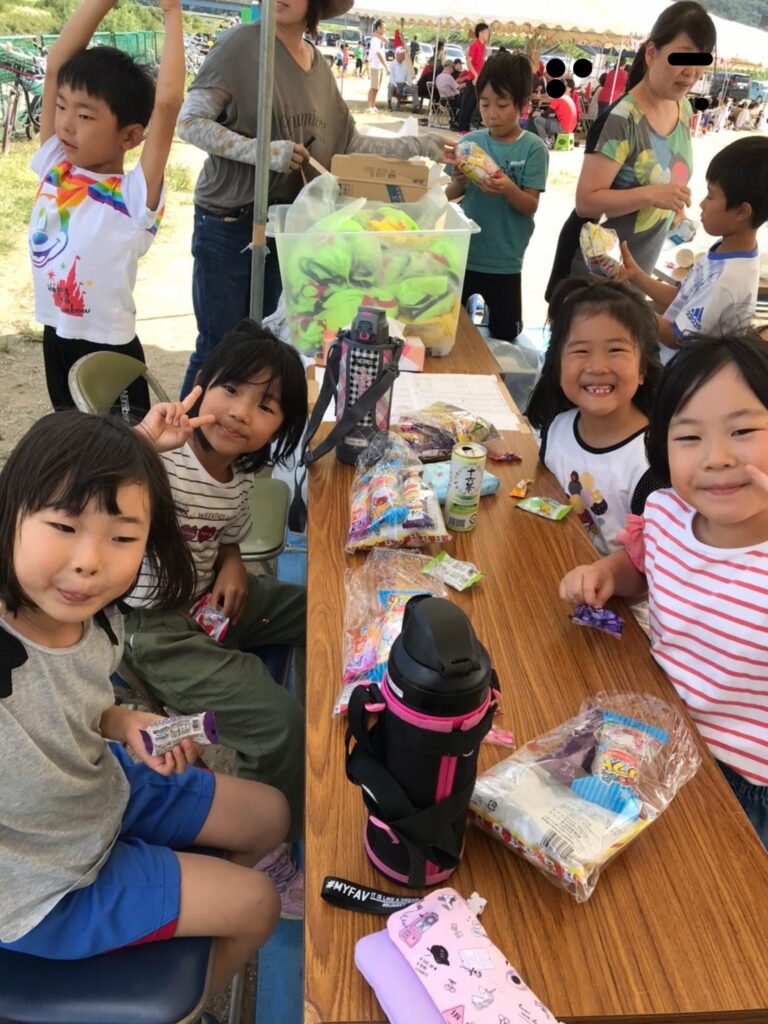 学区運動会で子ども達がおやつを食べている写真
